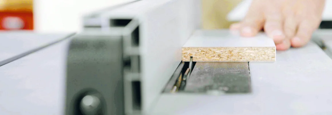 Person führt Holzplatte an Säge entlang